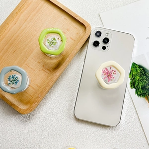 Detail of hexagonal phone grips featuring real dried flowers and gold bead accents