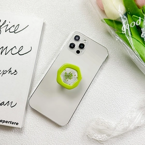 Green hexagonal resin phone grip with dried flowers attached to a white smartphone