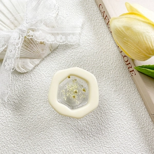 Close-up of hexagonal resin phone grip with white dried flowers and gold beads detailing