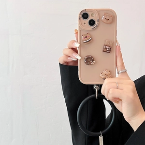 Beige iPhone case featuring 3D cartoon bear and donut charms with a black ring strap