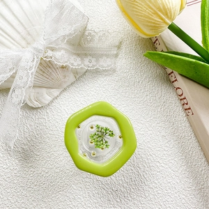 Macro detail of hexagonal resin phone grip with green dried flowers and gold beads