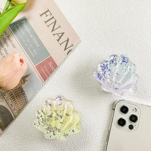 Detailed close-up of shell-shaped glitter phone sockets with sequins on white texture