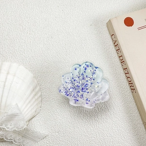 Detail of seashell phone socket with blue sequins, gold foil and pearls in resin