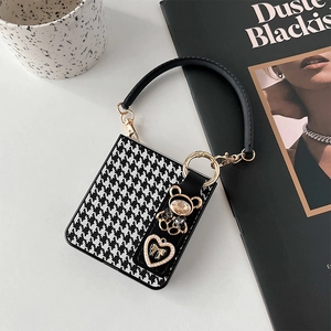 Detail of houndstooth mini bag charm featuring a golden rhinestone bear and heart pendant