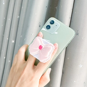 Close-up of pink bow phone grip with lace texture on a light green smartphone