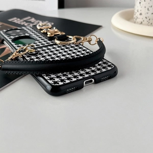 Close-up of houndstooth phone case featuring a gold metal handle and heart charm