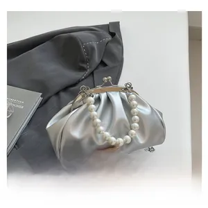 Detail of silver metallic cloud bag with large pearl handle and metal chain strap