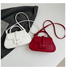 Close-up of pearl white and burgundy lychee leather handbags with gold buckles