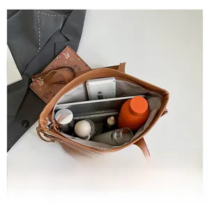 Top view of spacious brown tote interior with tablets, bottles, and office supplies
