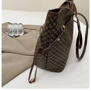 Detail view of printed tote bag with brown leather trim and golden metal rivet accents
