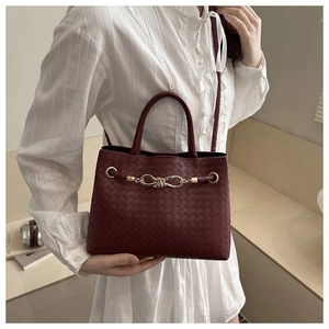 Détail du sac à main tressé bordeaux avec chaîne dorée et texture cuir élégante