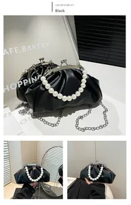Detail of black pleated cloud bag featuring large pearl handle and silver metal chain strap