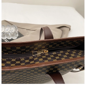 Close-up of golden metal zipper and vintage floral pattern on brown leather tote bag