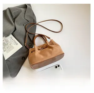 Brown suede bucket bag styled with a gray blazer and smartphone for size scale
