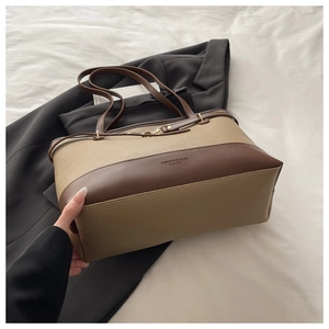 Detail of contrast color tote bag showing lychee pattern faux leather and gold lettering