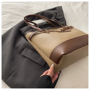 Detail view of large contrast tote bag with lychee texture leather on black suit background