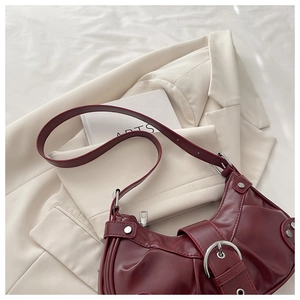 Detail of burgundy pleated leather bucket bag with silver hardware on white background