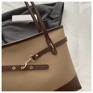Close-up of khaki pebbled leather tote bag featuring brown trim and gold hardware accents