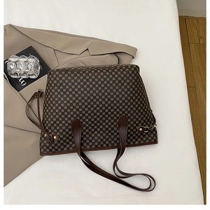 Close-up of a vintage tote bag with geometric print, brown leather handles and gold metal buckles
