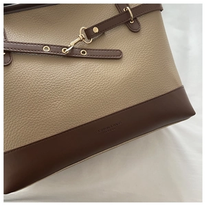 Detailed view of beige lychee leather stitching and gold hardware on tote bag