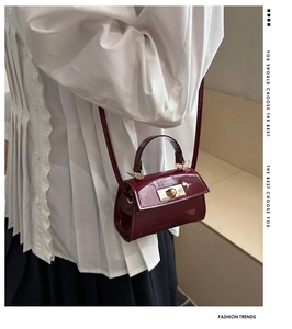 Detail of burgundy patent leather mini crossbody bag with gold hardware and fine strap