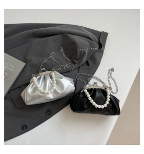 Detail showing silver and black pleated dumpling bags with pearl handles and metal chains