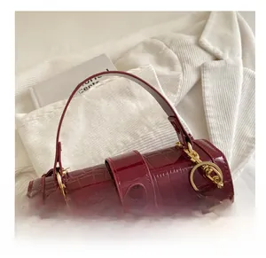 Detail of wine red crocodile embossed leather handbag with glossy finish and cherry charm