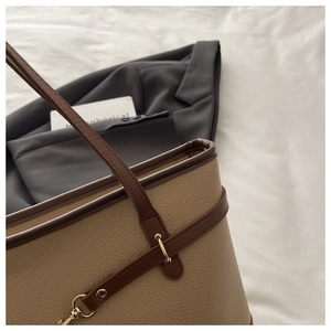 Close-up of beige litchi grain leather tote bag with dark brown trim and gold hardware