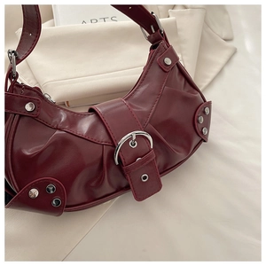 Detail of burgundy leather hobo bag with silver rivets and decorative buckle strap