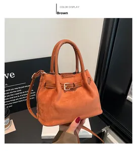 Detailed view of a brown suede bucket bag with gold buckle and adjustable strap