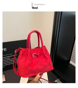 Detail of red suede tote bag showing soft matte texture and decorative buckle detail