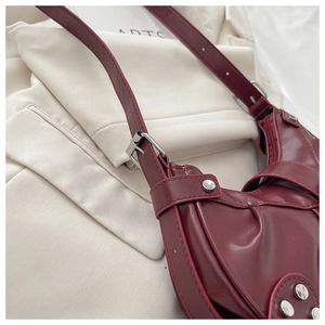 Close-up of burgundy semi-moon tote bag with silver rivets and adjustable strap details