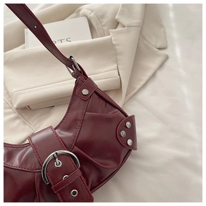 Detail of burgundy bucket bag with pleated leather texture and silver buckle hardware