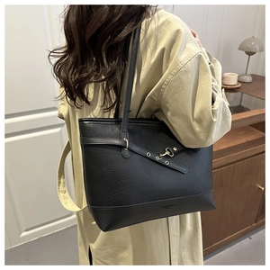 Detail shot of black pebbled leather tote bag with gold hardware worn in a lifestyle setting