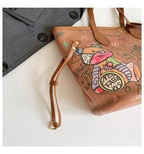 Macro detail of brown tote bag featuring graffiti prints and cartoon bear pattern