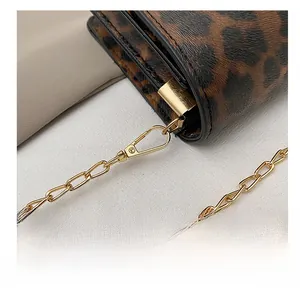Detail of light gold metal spring hook and chain on a leopard print leather shoulder bag