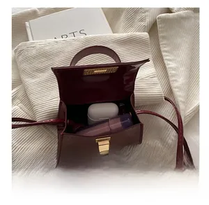 Detailed interior of glossy burgundy patent leather mini flap bag with gold metal twist lock