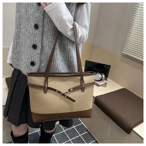 Close-up of contrast leather tote bag with lychee grain texture and buckle strap