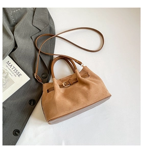 Vue de dessus d'un sac seau en daim marron avec poignées en cuir et bandoulière assortie