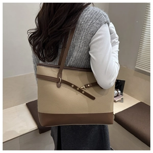 Detail of a large beige lychee texture tote bag with brown leather trim on a model