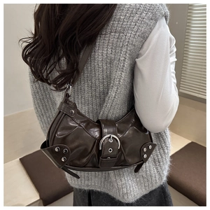 Detail of dark brown leather crescent bag with silver studs and buckle worn by a model