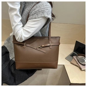 Detail of dark brown lychee leather tote bag with stylish metal buckle on shoulder