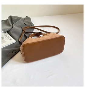 Détail d'un sac seau minimaliste avec surpiqûres marron et textures de cuir poli