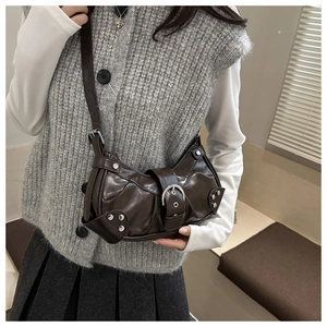 Detail of vintage brown leather bag featuring large silver buckle and pleated texture