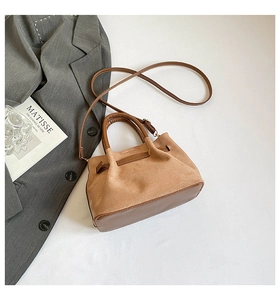 Détail du sac cabas en daim beige avec poignées en cuir marron foncé et bandoulière