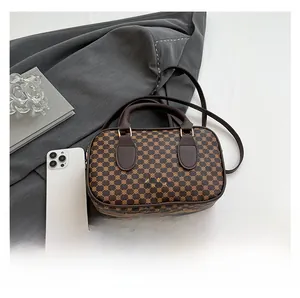 Brown geometric print crossbody bag next to a smartphone for size reference
