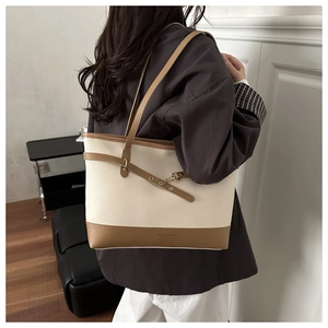 Detailed side view of cream and brown tote bag with metal hook and leather texture