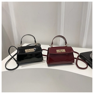 Detail of mini patent leather handbags in black and burgundy with gold twist locks