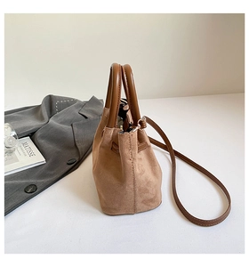 Vue détaillée du sac seau en daim beige avec des poignées marron foncé et des coutures