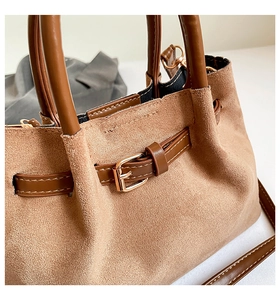 Détails de la texture daim et de la boucle en métal doré sur un sac seau marron chic